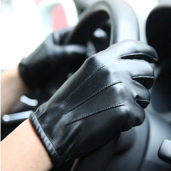 Gants de conduite en similicuir noir simples ici portés au volant d'une voiture.